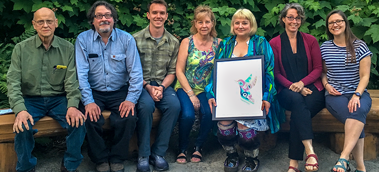 Paneen and her family at the Raven's Feast event. Photo courtesy of Paneen Petersen Image of Paneen with a serigraph from Marvin Oliver sitting with her father, brother, nephew-in-law, sister, friend and niece.