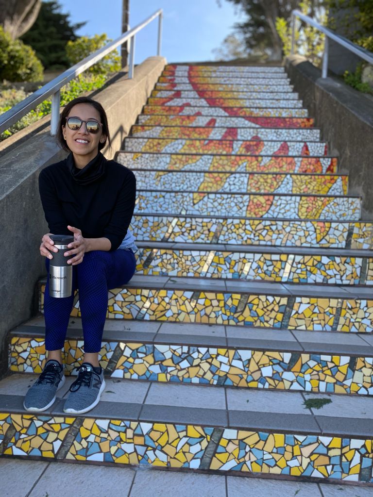 Jessica Barreto Guacaneme sitting on colorful steps with a coffee cup in hand.