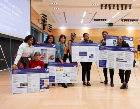 MPH students holding their practicum presentation posters.